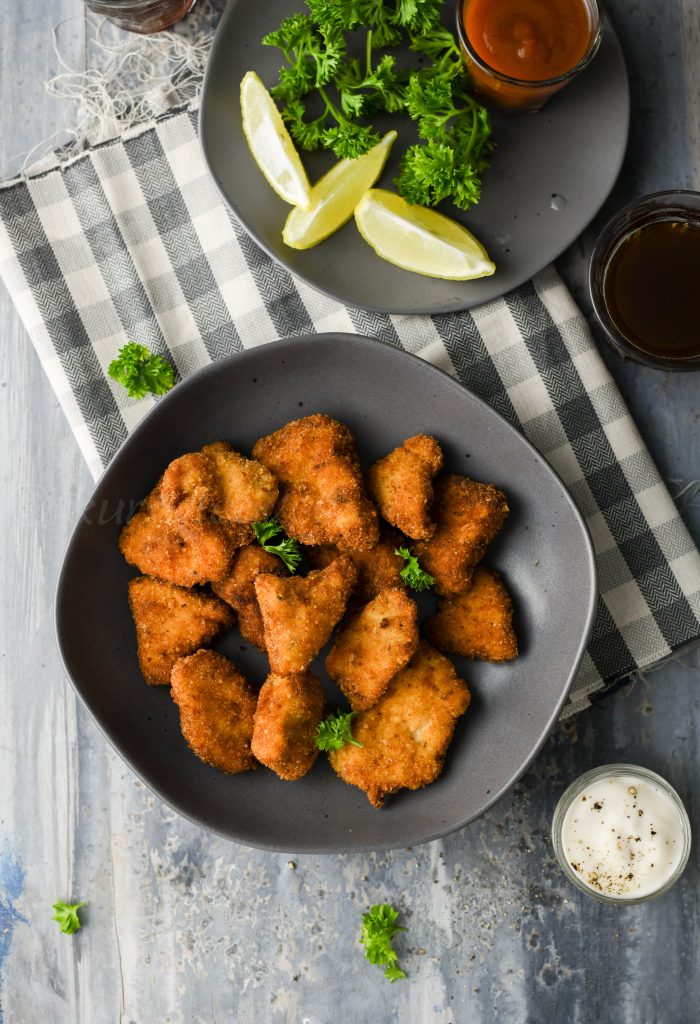 chicken nuggets with lemon wedges parsley tomato ketchup and beverage