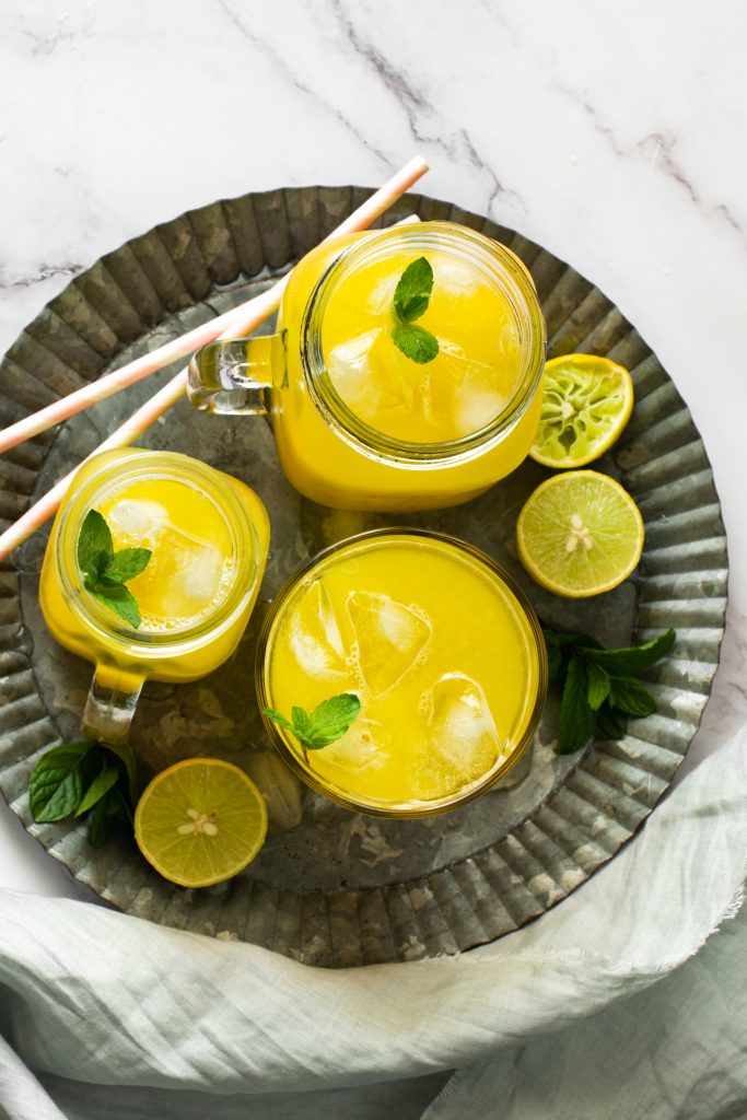 Refreshing mango lemonade with lemon and mint leaves on a tray